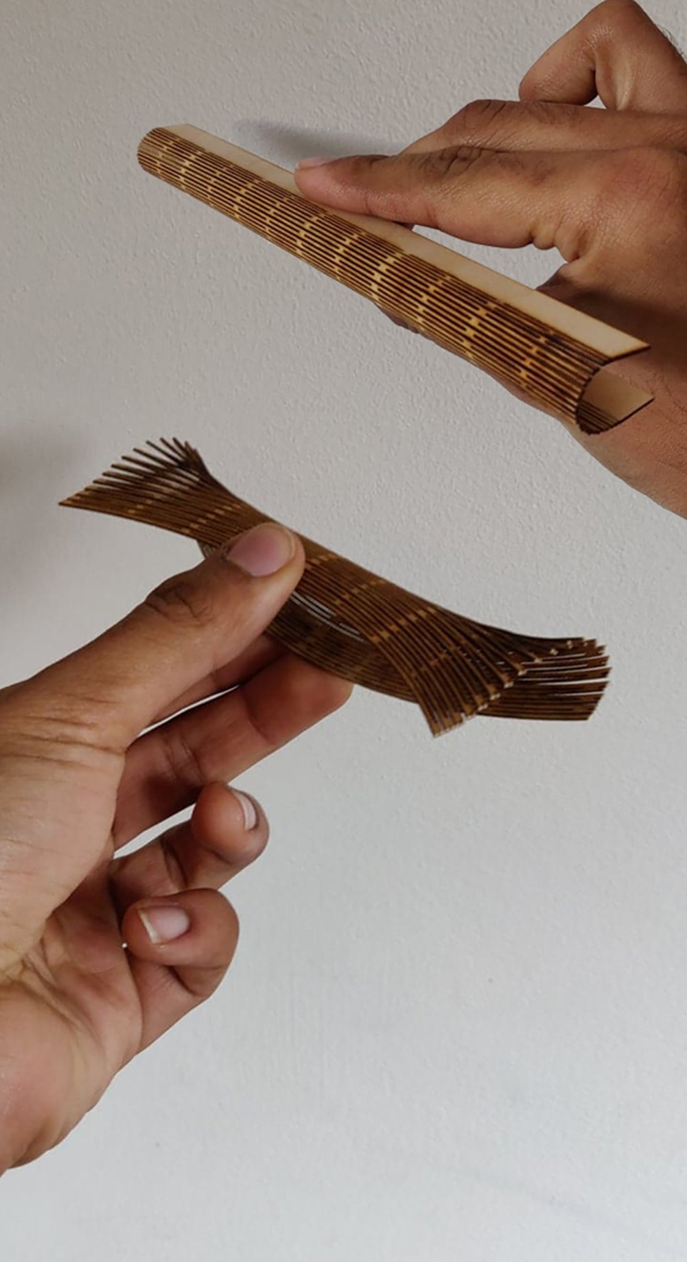 Hands flexing a laser-cut living-hinge panel